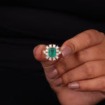 Hand holding a ring with an emerald and diamond design against a black background, Green Emerald Cut CZ Stone Engagement Ring – 14K Yellow Gold Wedding Ring