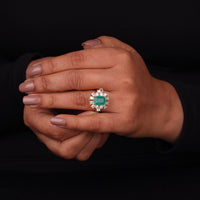 Hand wearing a ring with a green gemstone and diamond accents on a black background, Emerald Cut Green CZ Stone Wedding & Engagement Ring in 14K Yellow Gold