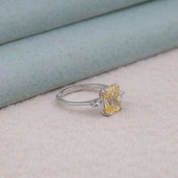 Silver ring with a yellow gemstone on a light gray surface, CZ fashion ring, colorful CZ ring, statement gemstone ring, yellow radiant cut ring, three stone CZ jewelry, CZ wedding ring, affordable gemstone ring, elegant CZ stone ring, triangle cut CZ design, radiant and triangle ring,