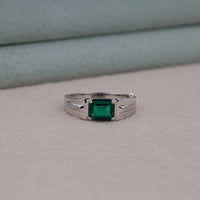 Silver ring with a green gemstone on a neutral background