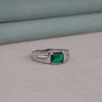 Silver ring with a green gemstone on a neutral background