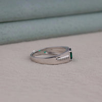 Silver ring with a green gemstone on a neutral background