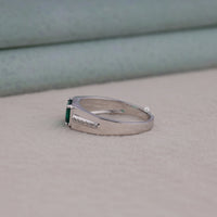 Silver ring with a green gemstone on a beige surface