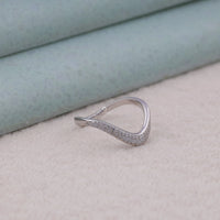 Silver ring with small diamonds on a light fabric background, delicate curved band, engagement ring pairing band, Moissanite wedding jewelry, elegant Moissanite band