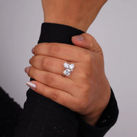 Hand wearing a silver ring with two large diamonds on a plain background, Multi Shape Moissanite Ring – Oval, Pear, Cushion & Round Five Stone Anniversary Band