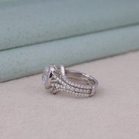 Two silver rings with diamond accents on a light background, Oval Moissanite Halo Engagement Ring with Split Shank + Coordinating Guard Wedding Band
