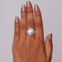 Diamond ring on a hand with glittery nail polish against a gray background, Luxury Oval Moissanite Engagement Ring with Halo & Split Shank + Enhancer Band