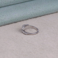 Silver ring with gemstones on a beige surface, Graduated Moissanite Ring, Round Moissanite Bypass Ring, Open Gap Spiral Ring