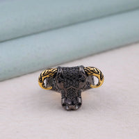 Bull skull ring with gold horns on a light surface, Gothic Ox Ring, Unique Skull Ring for Him, Close-up of an ox skull ring crafted in 925 sterling silver, featuring black round stones and gold-tone engraved horns — bold Viking and biker style men’s jewelry.