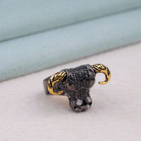 Silver and gold elephant-shaped ring on a light surface with a neutral, background,  stylish gothic ring, biker fashion accessory, animal-inspired ring, skull charm jewelry, heavy metal ring, fashionable skull design, warrior ring, badass ring for men
