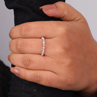 Close-up of a hand wearing a diamond ring on a neutral background, Minimalist Moissanite Wedding Ring, Round Cut Moissanite Eternity Band, Dainty Moissanite Wedding Band