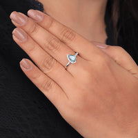 Close-up of a hand wearing a ring with a blue gemstone on a neutral background, Pear Cut Moissanite Engagement Ring, Aqua and Green Moissanite Wedding Band, Half Halo Moissanite Bridal Ring