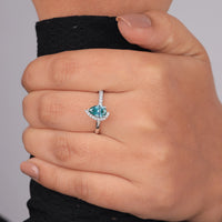 Hand wearing a ring with a blue gemstone on a gray background, Unique Colorful Moissanite Engagement Jewelry, 14K Gold Pear Shape Wedding Ring