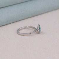 Silver ring with a blue gemstone on a light gray surface, Affordable Pear Cut Wedding Ring, Contemporary Half Halo Wedding Jewelry, Statement Colorful Moissanite Bridal Ring