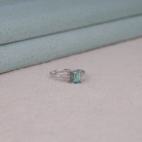 Silver ring with a green gemstone on a light gray surface