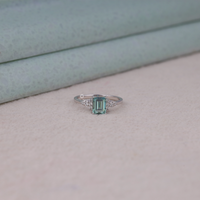 Silver ring with a green gemstone on a light gray surface