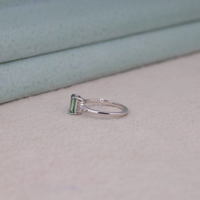Silver ring with a green gemstone on a light background