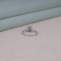 Silver ring with a green gemstone on a beige surface