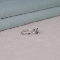 Silver ring with a green gemstone on a light gray surface