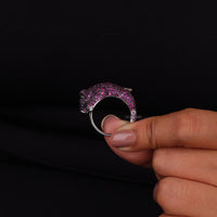 Hand holding a pink and silver ring with a black background