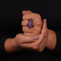 Hand wearing a purple glittery ring on a black background