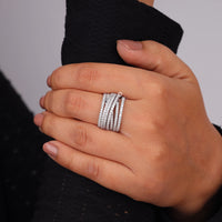 Hand wearing multiple silver rings on a neutral background, Dainty Multi Row Moissanite Anniversary Ring For Women, Elegant Round Moissanite Layered Wedding Band