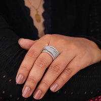 Hand wearing multiple silver rings with a dark background, Round Moissanite Criss Cross Multi Layer Wedding Band Ring