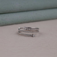 Silver ring with small diamonds on a light gray surface