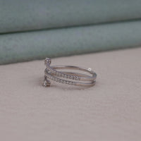 Silver ring with small diamonds on a light gray surface