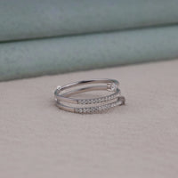 Two silver rings with diamond accents on a neutral background