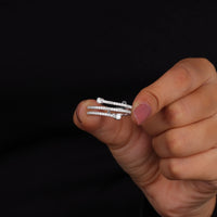 Hand holding a set of diamond earrings against a black background
