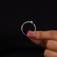 Silver ring held by a hand with pink nail polish against a black background