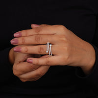 Close-up of a hand wearing two silver rings on a black background