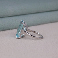 Silver ring with a large blue gemstone on a light gray surface