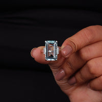 Hand holding a diamond ring against a black background