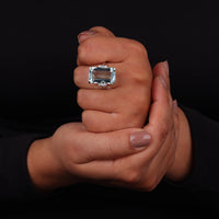 Hand wearing a diamond ring with a black background
