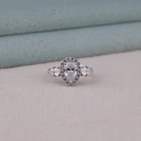 Silver ring with heart-shaped center stone on a light gray surface