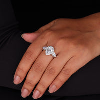 Close-up of a hand wearing a diamond ring against a black background