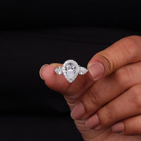 Diamond ring held between fingers against a black background