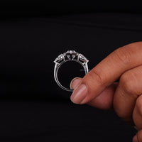 Silver ring with a diamond held between fingers against a black background