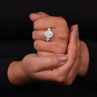 Diamond ring held between two hands against a black background