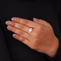 Hand wearing a diamond ring against a black background, Oval, Marquise & Round Moissanite Leaf Inspired Engagement Ring
