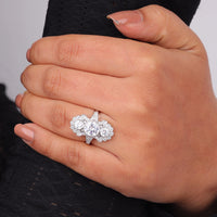 Silver ring with multiple gemstones on a hand against a neutral background, Vintage Inspired Three Stone Moissanite Ring, Art Deco Milgrain Engagement Ring