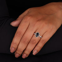 Hand wearing a ring with a black and white design on a dark background