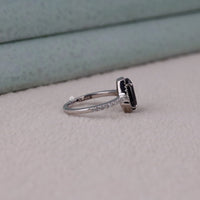 Silver ring with a black gemstone on a light gray surface
