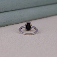 Silver ring with a black stone on a textured surface