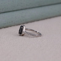 Silver ring with a black gemstone on a light gray surface