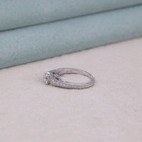 Silver ring with a diamond on a light gray surface, timeless Moissanite wedding ring, affordable Moissanite bridal jewelry, halo-free wedding ring, geometric vintage ring, Moissanite ring with vintage charm, unique Moissanite ring design, fine Moissanite ring