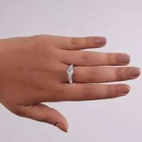 Hand wearing a silver ring with a diamond on a light gray background, Moissanite ring for weddings, Art Deco style wedding band, Moissanite vintage style ring, classic bridal ring, Moissanite heirloom ring, vintage look wedding ring, diamond alternative bridal ring