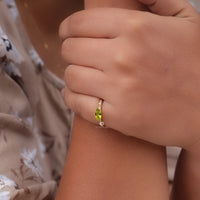 Close-up of a hand wearing a green gemstone ring with a blurred, background, Peridot CZ Promise Ring, Dainty Marquise Peridot Ring, Green Stone East West Engagement Ring